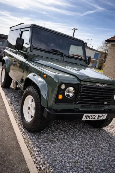 Green classic Land Rover Defender parked outside after a full exterior detail